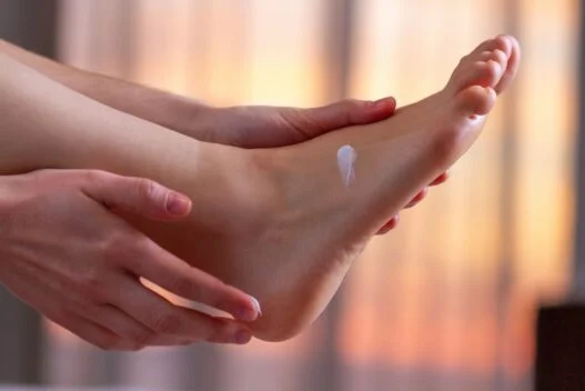 Kvinde der smører sine fødder med fugtgivende creme